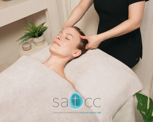 Lady laying down on a massage table covered by a grey towel receiving a scalp massage with the SATCC logo displayed over the top