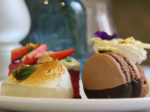 A close-up of a sweet afternoon tea plate with a chocolate macaron and meringue tart