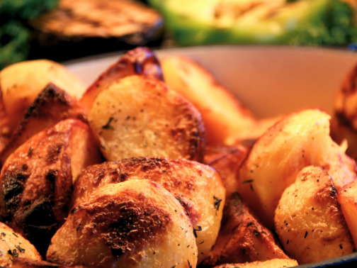 A close-up of a casserole dish filled with crispy seasoned roast potatoes