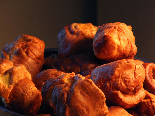 A close-up of a metal bowl filled with giant crispy Yorkshire puddings