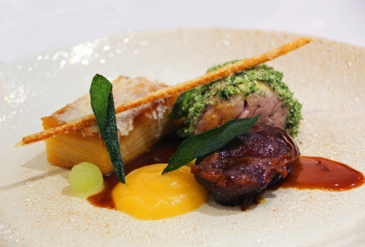 Close up of a beef and finely stacked potato dish with jus over the top