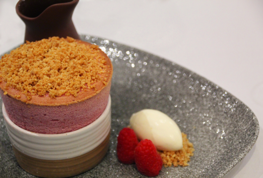 A fine dining pink raspberry souffle with raspberries and ice cream