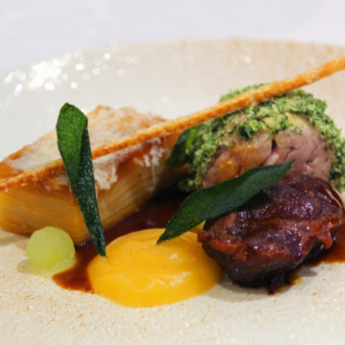 Close up of a beef and finely stacked potato dish with jus over the top