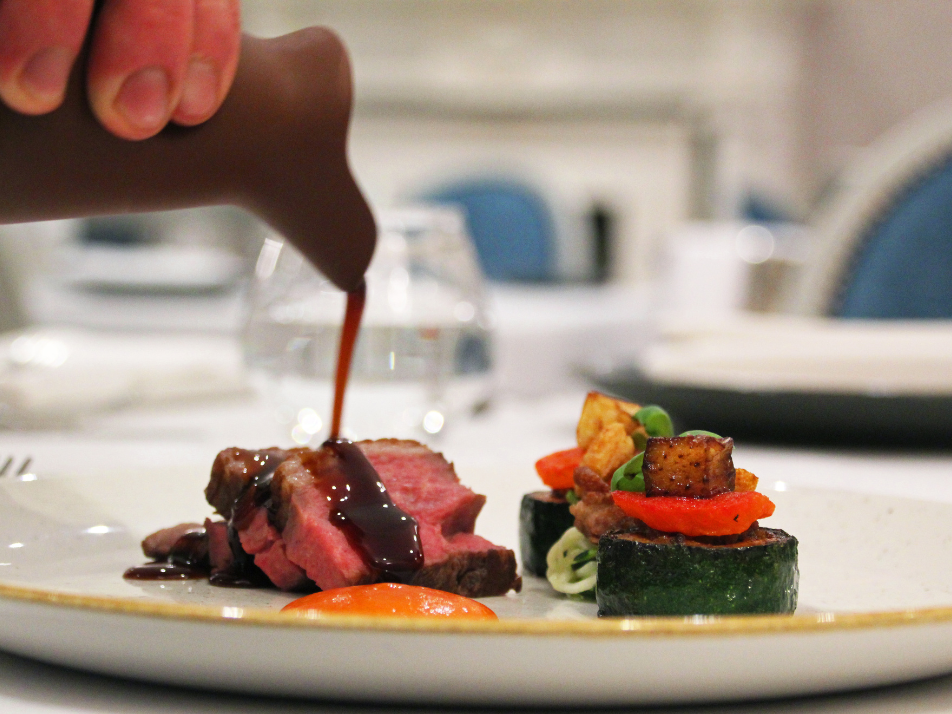 A Fine Dining medium rare Beef dish with a jus being poured over the top