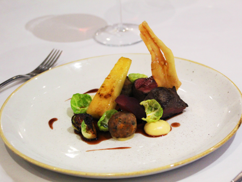 a fine dining potato and beef dish plated on gold trimmed white plate