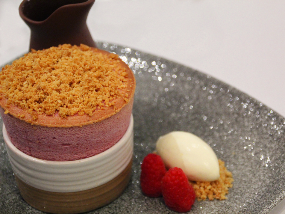 A fine dining pink raspberry souffle with raspberries and ice cream