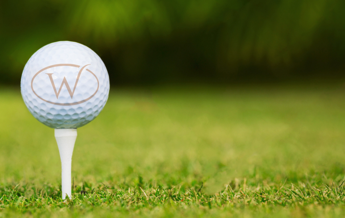 A golf ball with Whittlebury Park's gold logo on it on a golf fee