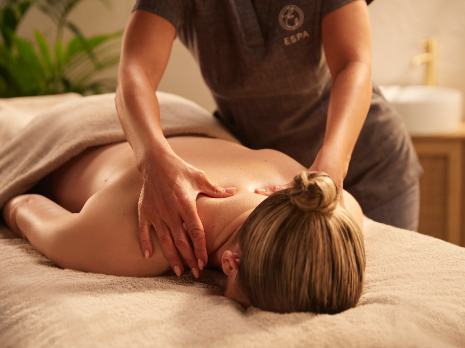 Lady laying on a massage bed receiving a shoulder massage from a spa therapist