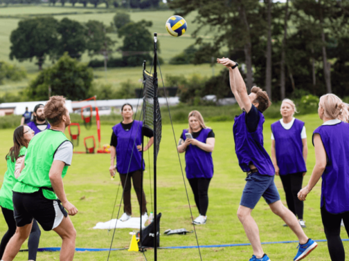 A group of people wearing blue and green sports bibs playing netball