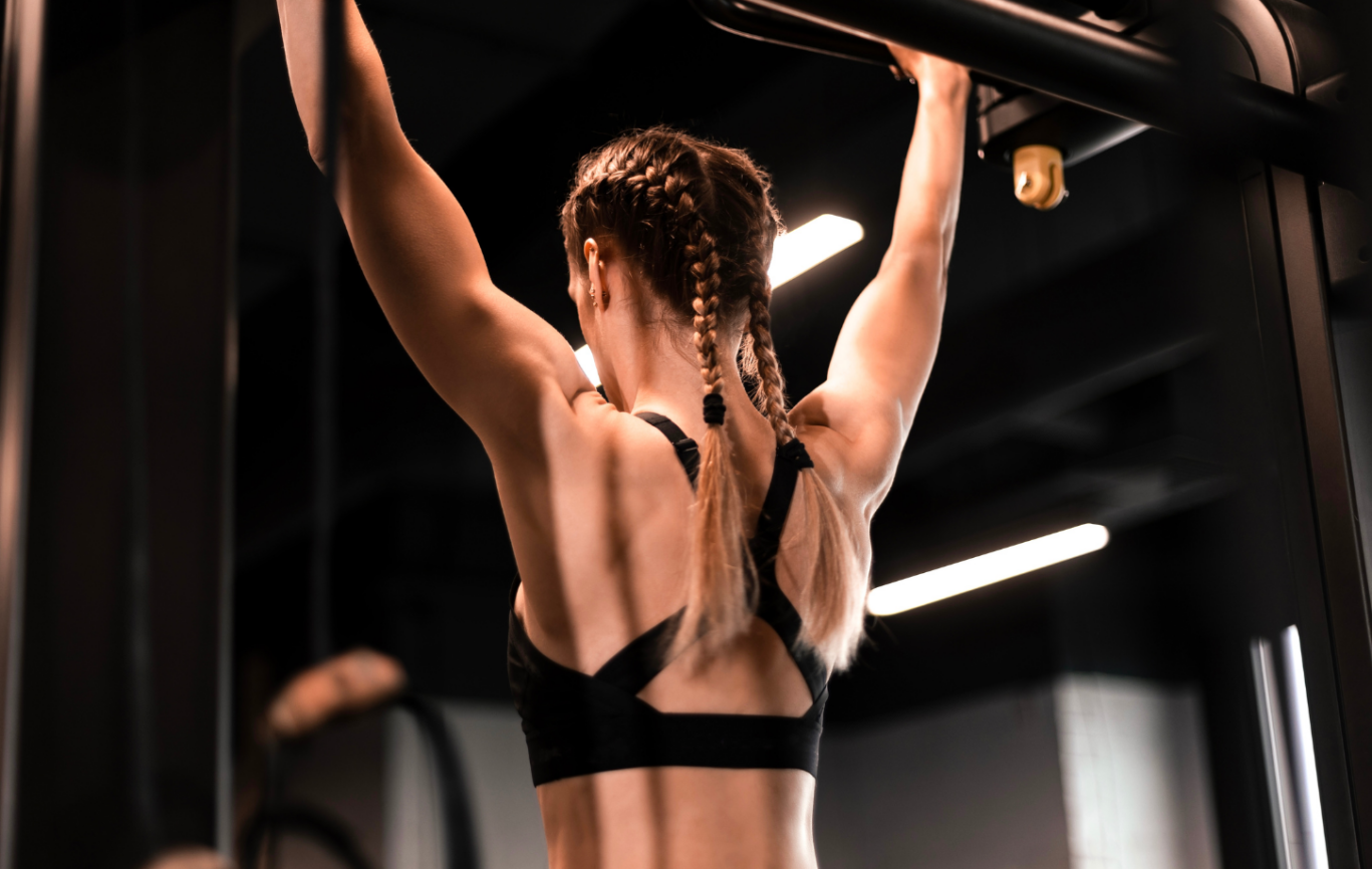 A woman at the gym performing a lat pull up exercise