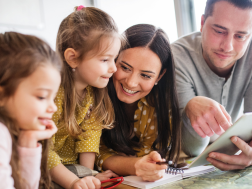 A family on a bed looking at an iPad