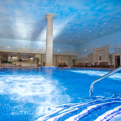Looking down a blue clear swimming pool with roman decor