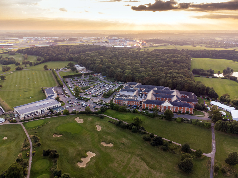 An aerial view of Whittlebury Park Estate and Silverstone Circuit in the background during a sunset