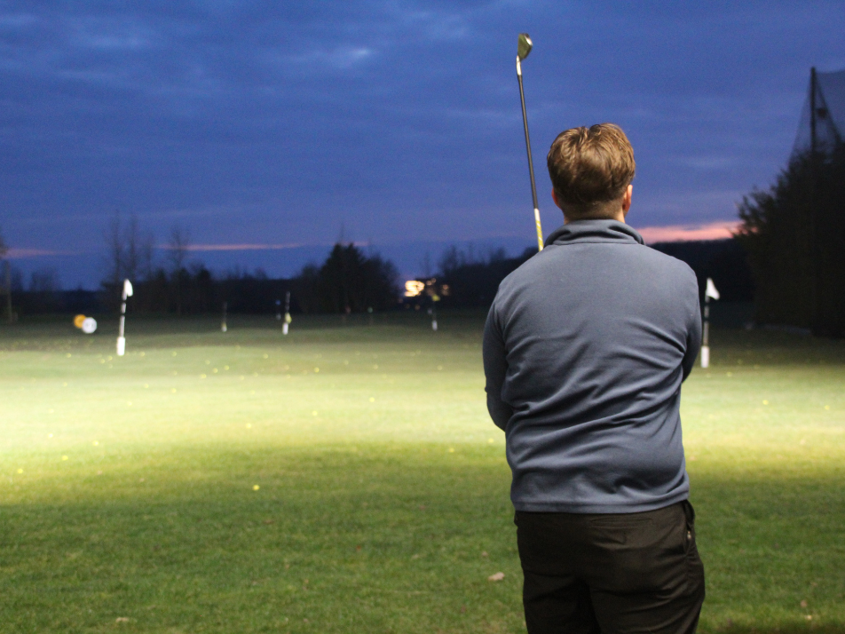 A golfer looking down a golfing range at night