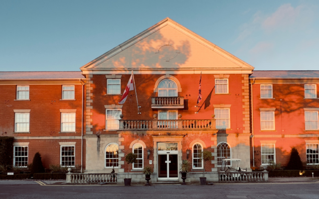 Whittlebury Hall hotel with light from a sunset hitting the front of the building