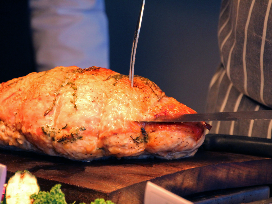 A carvery chef cutting into a roasted chicken