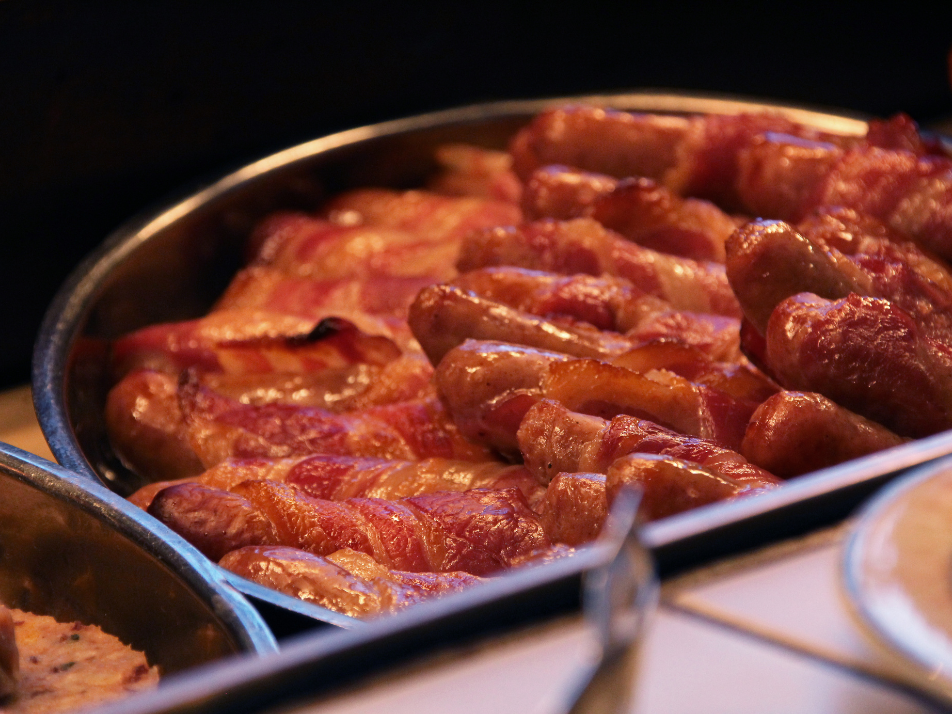 A metal serving bowl full of pigs in blankets