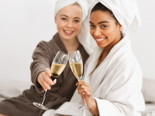 Two ladies in spa robes relaxing with a glass of prosecco each