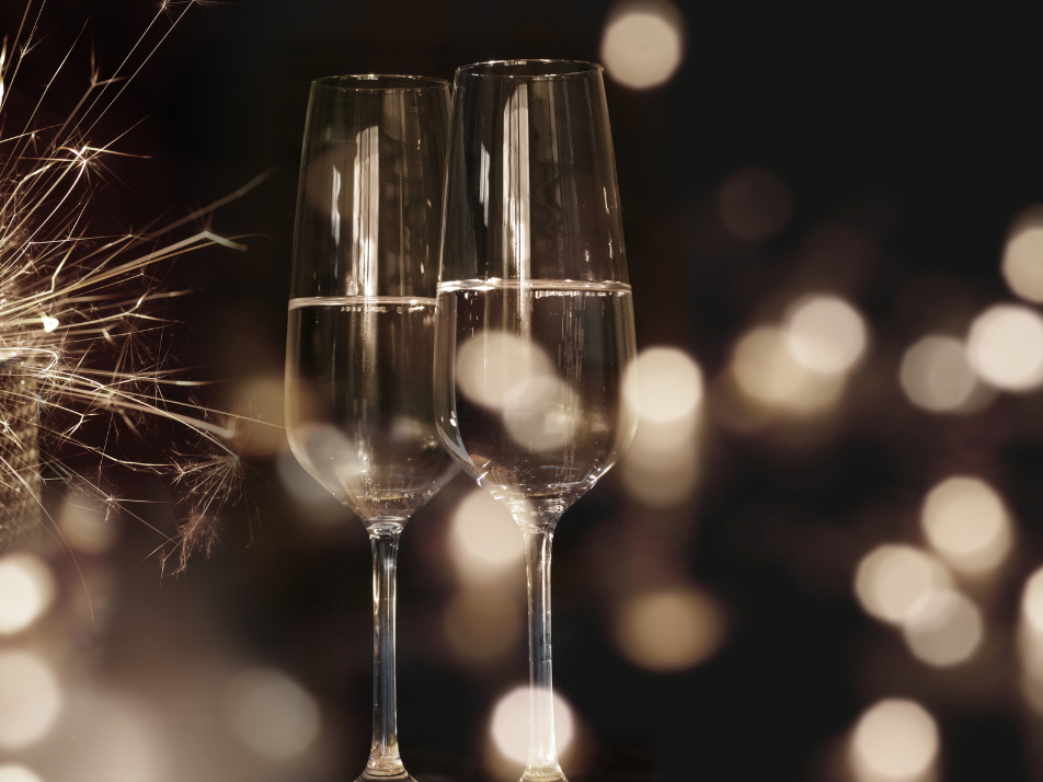 Two glasses of champagne flutes next to a sparkler