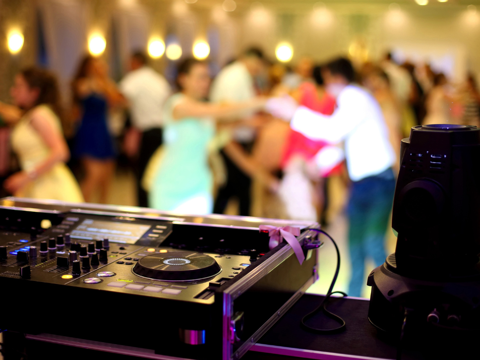 A DJ set overseeing a dancefloor full of people dancing