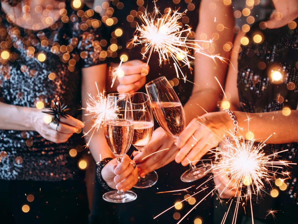 Glasses of champagne clinking together surrounded by sparklers